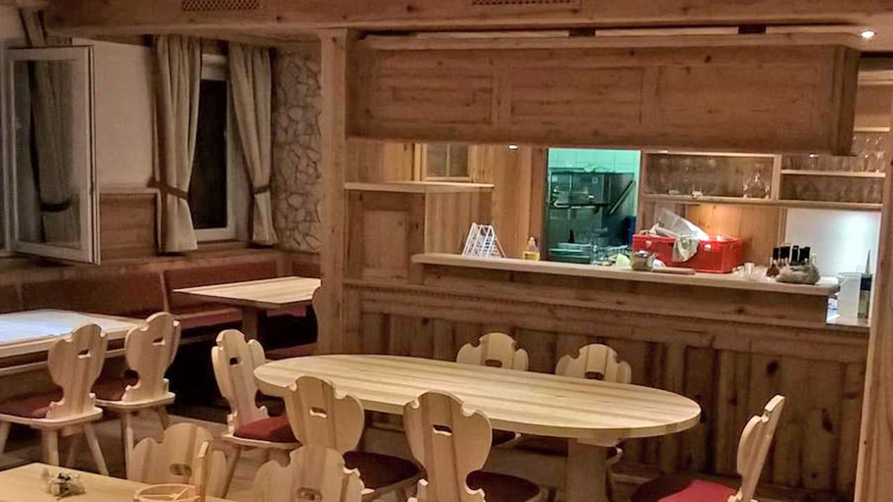 Rustikal eingerichteter Gastsaal mit mehreren Holztischen und Holzstühlen in einer Gastronomie