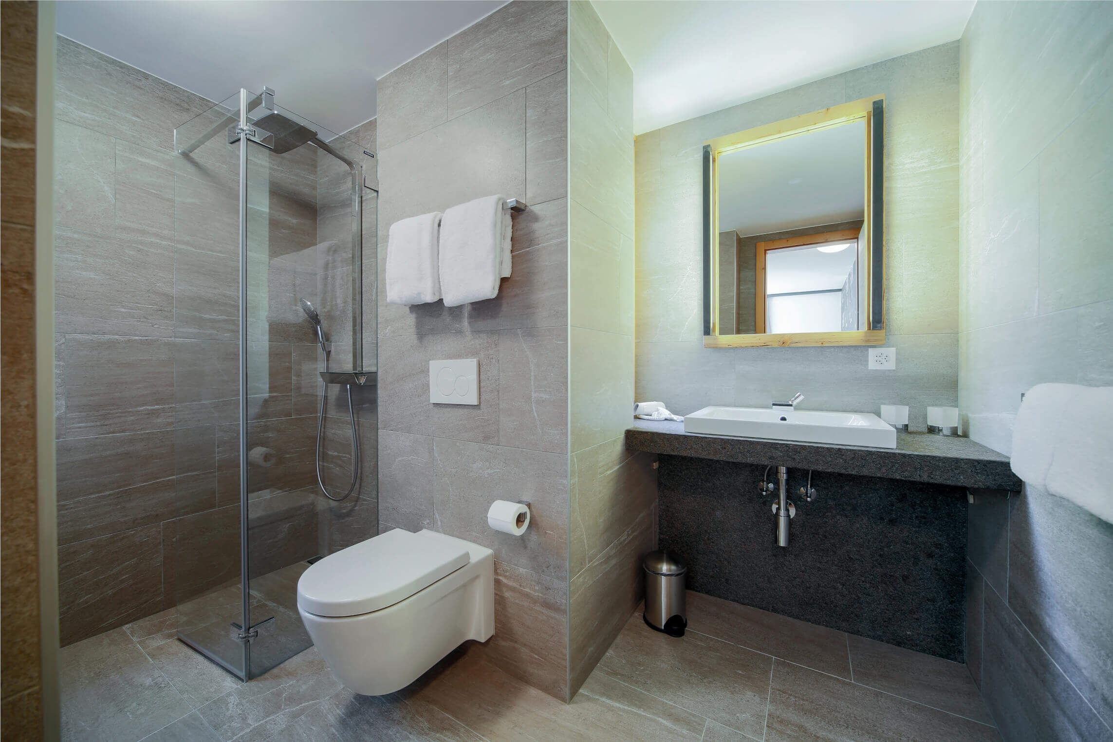 Badezimmer Einrichtung mit grauen Fliesen, Dusche und Toilette